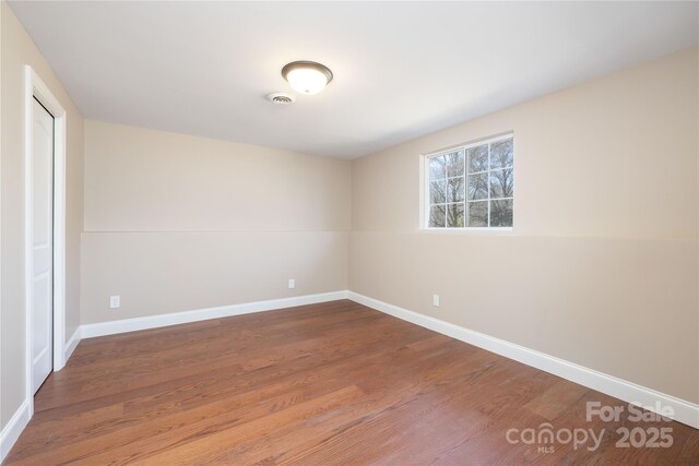 empty room with visible vents, baseboards, and wood finished floors