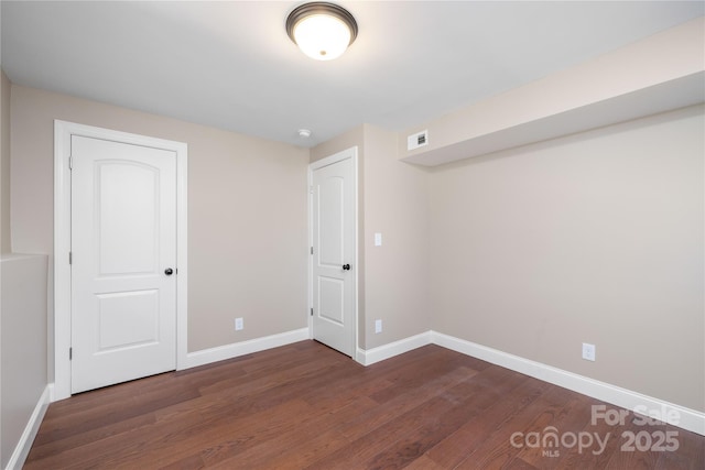 unfurnished room with visible vents, baseboards, and wood finished floors