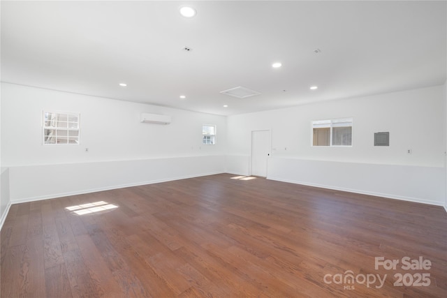 spare room with a wall unit AC, baseboards, dark wood-type flooring, and recessed lighting