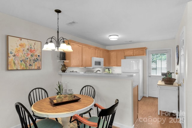 kitchen featuring a peninsula, white appliances, light brown cabinets, and light countertops