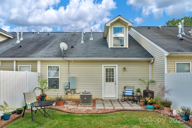 rear view of property featuring a yard, fence, central AC, and a patio