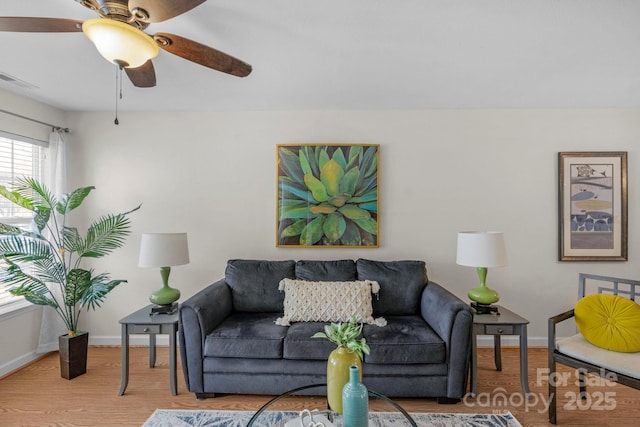 living area with a ceiling fan, wood finished floors, visible vents, and baseboards