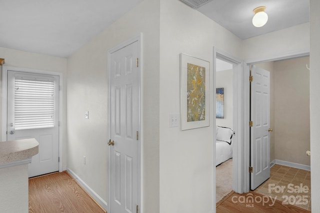 corridor featuring light wood-style floors and baseboards