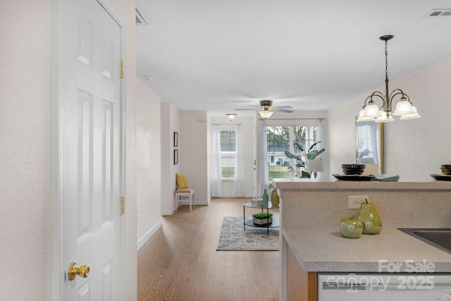 kitchen featuring light wood-style flooring, visible vents, light countertops, hanging light fixtures, and dishwasher