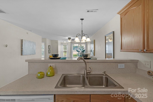 kitchen featuring dishwashing machine, a sink, visible vents, open floor plan, and light countertops