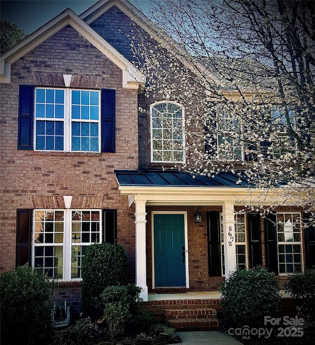 view of front of property with metal roof, brick siding, and a standing seam roof