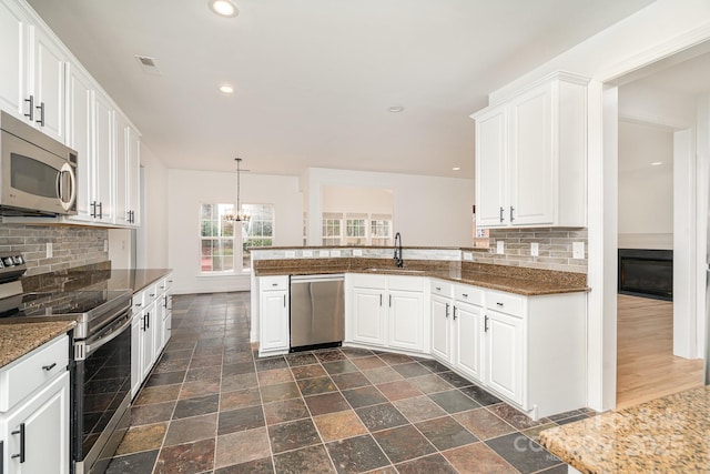 kitchen with recessed lighting, decorative backsplash, appliances with stainless steel finishes, white cabinets, and a sink