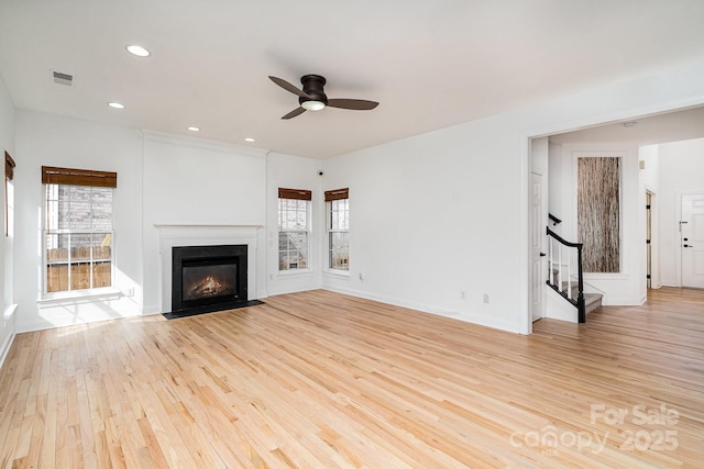 unfurnished living room featuring recessed lighting, visible vents, stairway, light wood-style flooring, and a fireplace with flush hearth