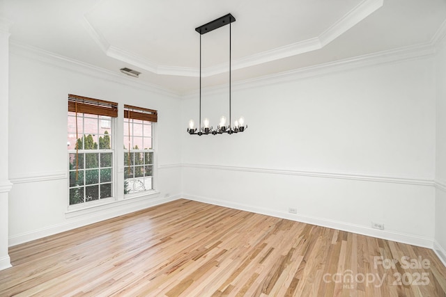 unfurnished dining area featuring visible vents, ornamental molding, a tray ceiling, light wood-type flooring, and a chandelier