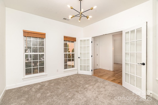 empty room with a chandelier, visible vents, baseboards, french doors, and carpet