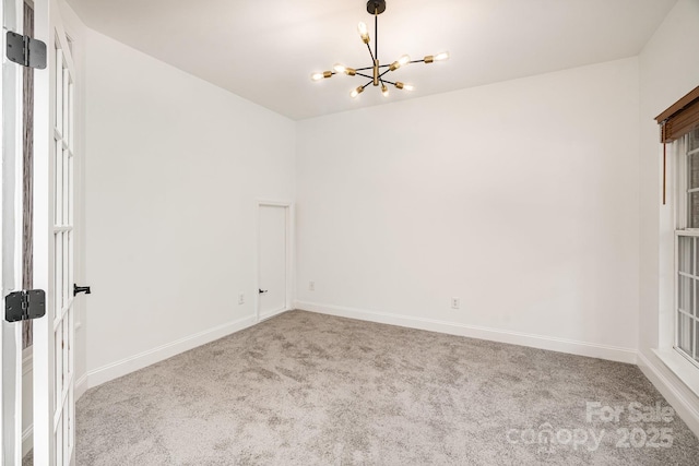 empty room featuring baseboards, carpet, and an inviting chandelier