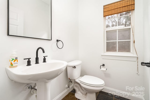 half bath featuring tile patterned flooring, baseboards, a sink, and toilet