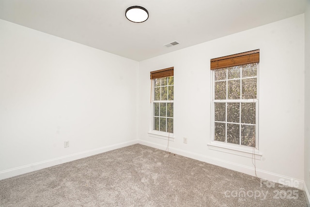 carpeted spare room with visible vents and baseboards