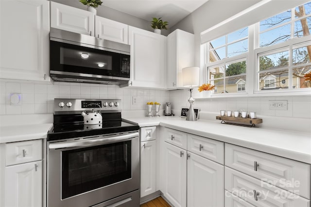 kitchen featuring decorative backsplash, white cabinets, and stainless steel appliances