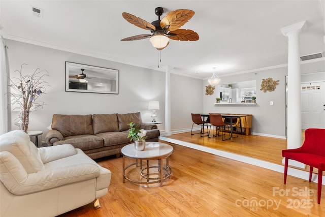 living room featuring wood finished floors, visible vents, ornate columns, and ornamental molding