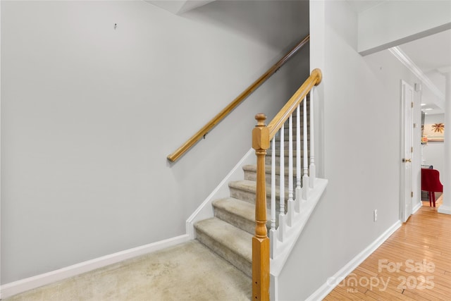 stairs featuring baseboards, wood finished floors, and ornamental molding