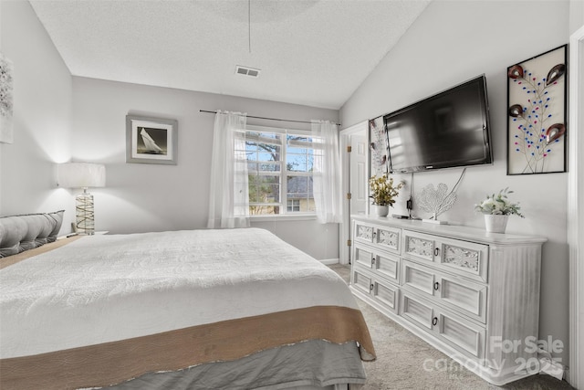 bedroom featuring lofted ceiling, light colored carpet, visible vents, and a textured ceiling