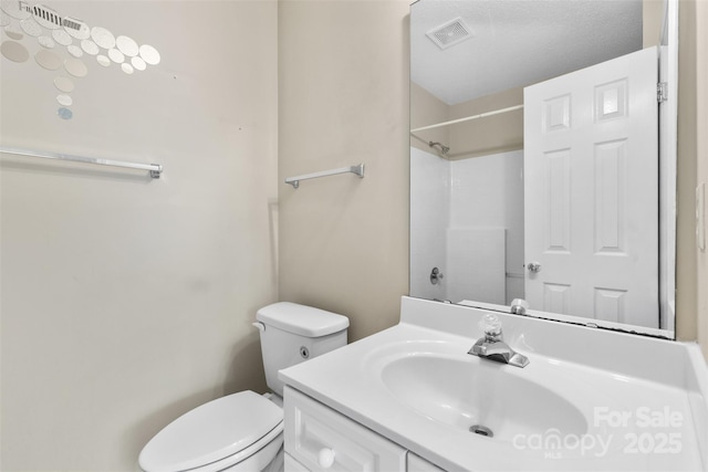 bathroom featuring visible vents, toilet, vanity, and walk in shower