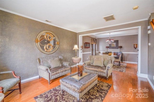 living area with visible vents, crown molding, baseboards, and wood finished floors