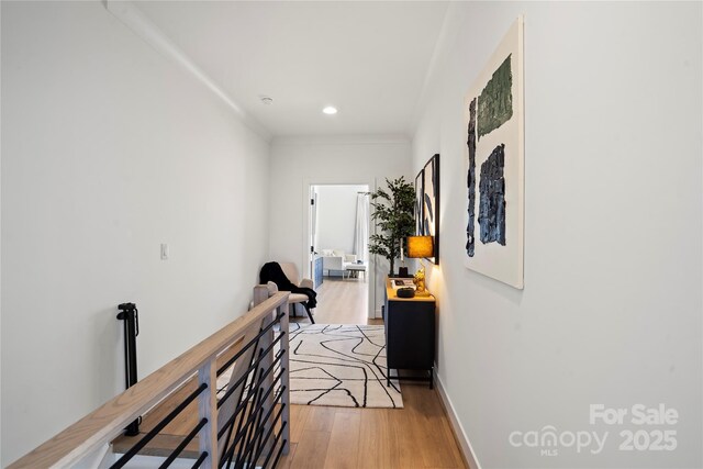 hall with light wood-style floors, baseboards, an upstairs landing, and recessed lighting