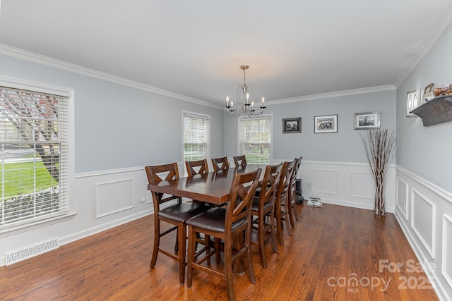 dining area with a wainscoted wall, visible vents, ornamental molding, dark wood finished floors, and a notable chandelier