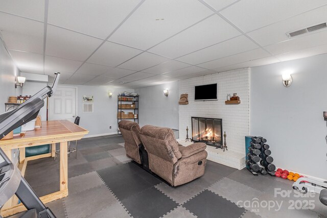 living room with baseboards, a fireplace, visible vents, and a paneled ceiling