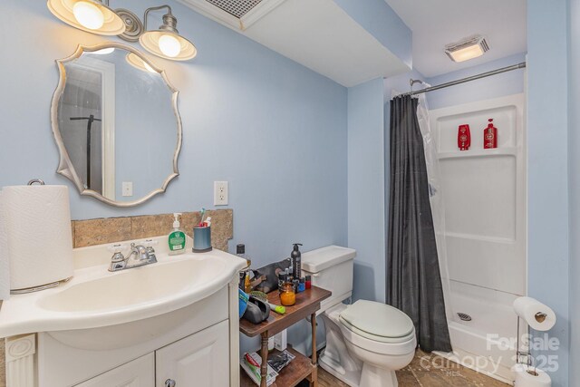 bathroom featuring visible vents, toilet, a stall shower, and vanity