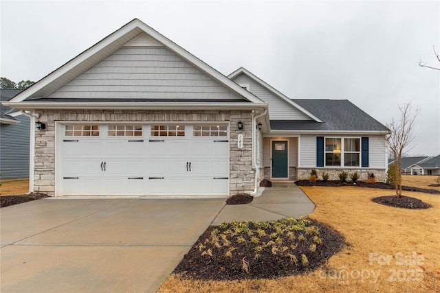 view of front of property with an attached garage, stone siding, and concrete driveway