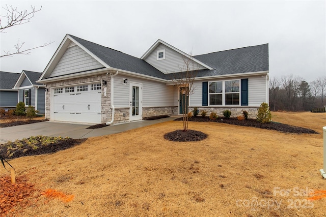 craftsman-style house with a front yard, stone siding, an attached garage, and concrete driveway