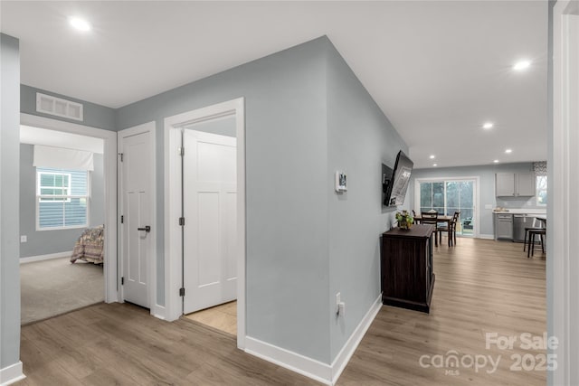 hallway with light wood-type flooring, baseboards, visible vents, and recessed lighting