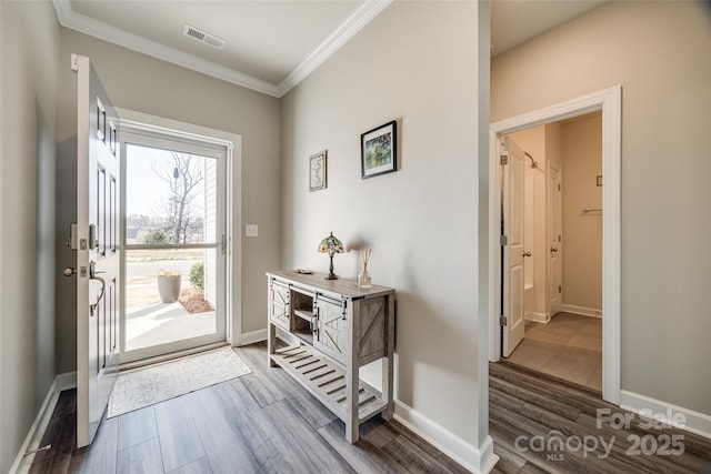 entryway featuring ornamental molding, visible vents, baseboards, and wood finished floors