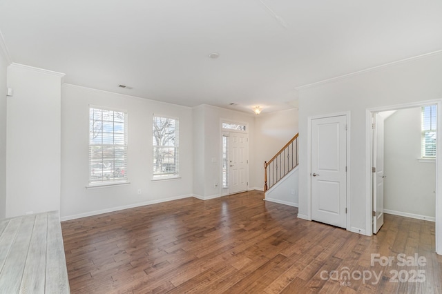 interior space featuring visible vents, ornamental molding, wood finished floors, baseboards, and stairs