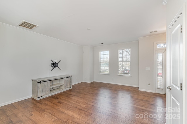 spare room with visible vents, baseboards, wood finished floors, and crown molding