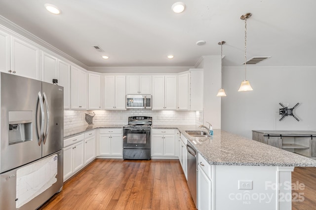 kitchen featuring visible vents, light wood-style flooring, appliances with stainless steel finishes, a peninsula, and decorative backsplash