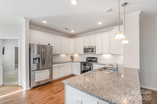 kitchen featuring a peninsula, backsplash, appliances with stainless steel finishes, and a sink