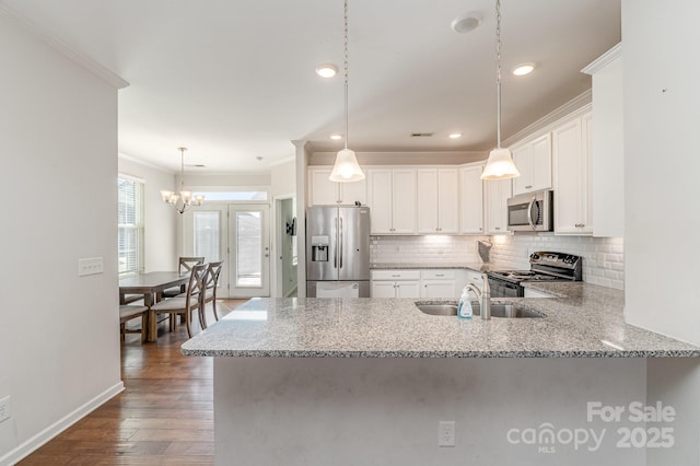 kitchen with a peninsula, a sink, stainless steel appliances, crown molding, and tasteful backsplash