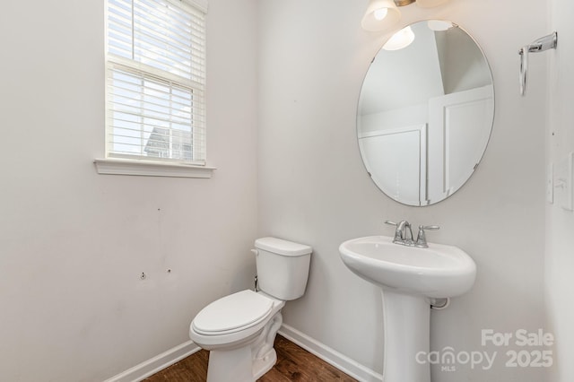 bathroom with a sink, toilet, baseboards, and wood finished floors