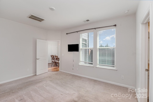 carpeted spare room featuring baseboards and visible vents