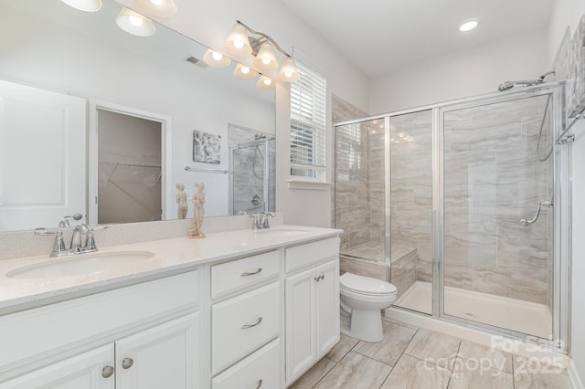 full bathroom with a sink, toilet, double vanity, and a shower stall