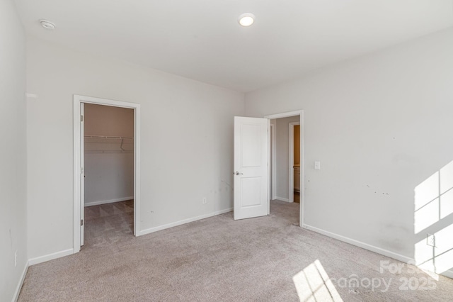 unfurnished bedroom featuring baseboards, carpet floors, and a walk in closet