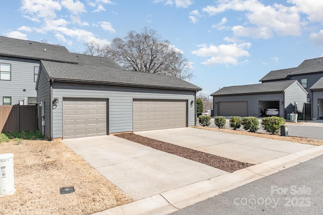 view of front of home with a garage, roof with shingles, and fence