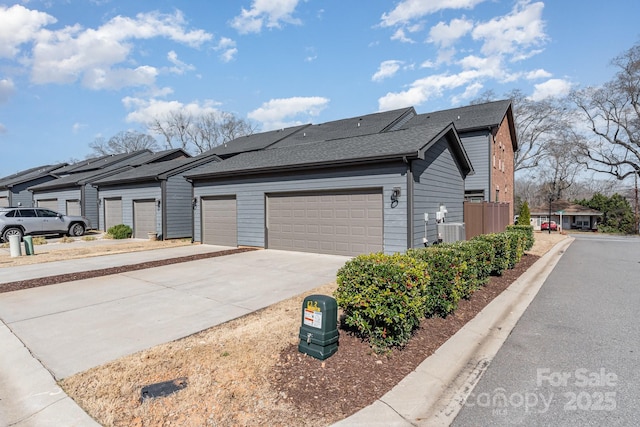 view of front of home featuring a residential view, concrete driveway, a shingled roof, a garage, and central AC unit