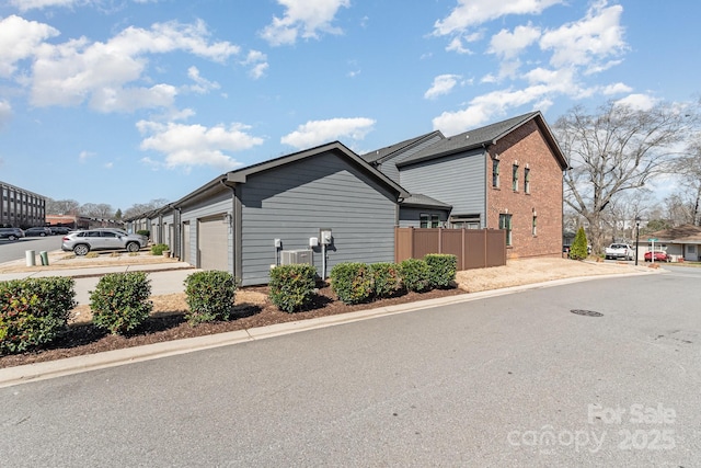 view of side of property featuring an attached garage, driveway, and fence