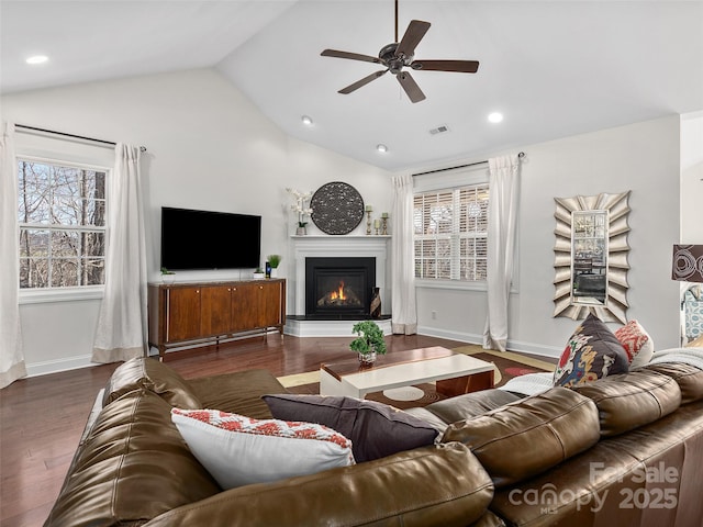 living area featuring lofted ceiling, wood finished floors, visible vents, and a healthy amount of sunlight