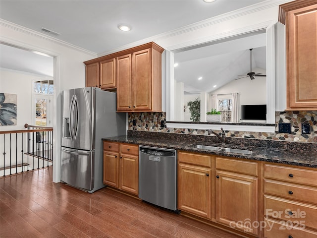 kitchen featuring dark wood-style flooring, a sink, appliances with stainless steel finishes, decorative backsplash, and crown molding