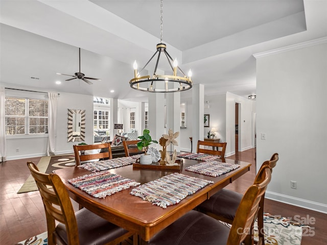 dining area with a raised ceiling, visible vents, wood finished floors, baseboards, and ceiling fan with notable chandelier