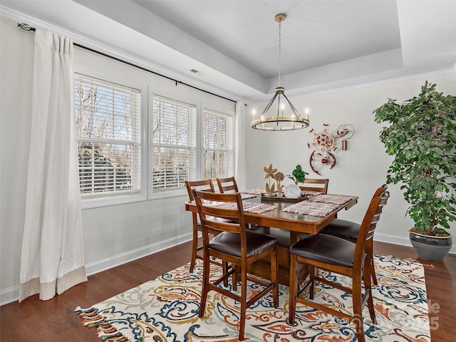 dining room with a tray ceiling, a notable chandelier, dark wood finished floors, and baseboards