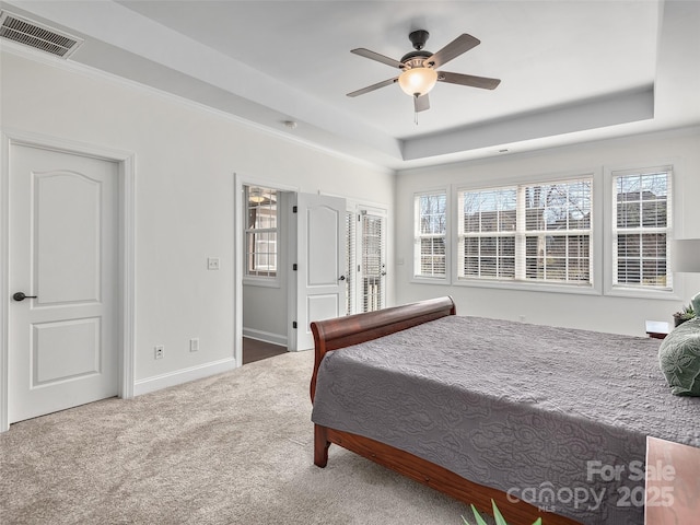 bedroom with ceiling fan, carpet flooring, visible vents, baseboards, and a tray ceiling