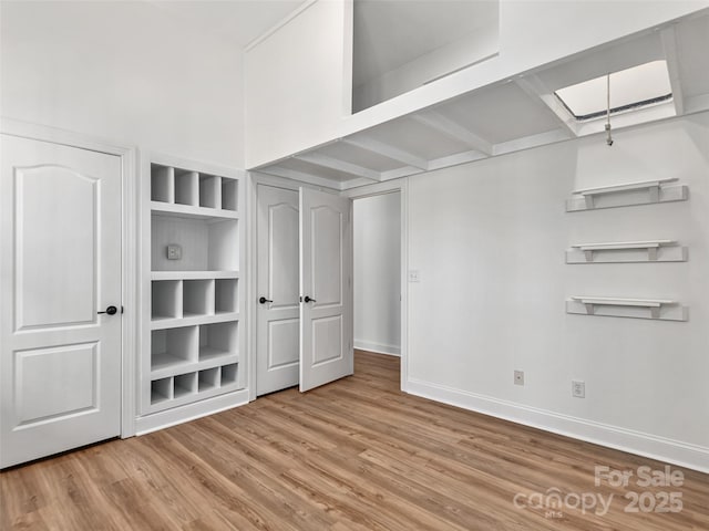 interior space with built in shelves, baseboards, and wood finished floors