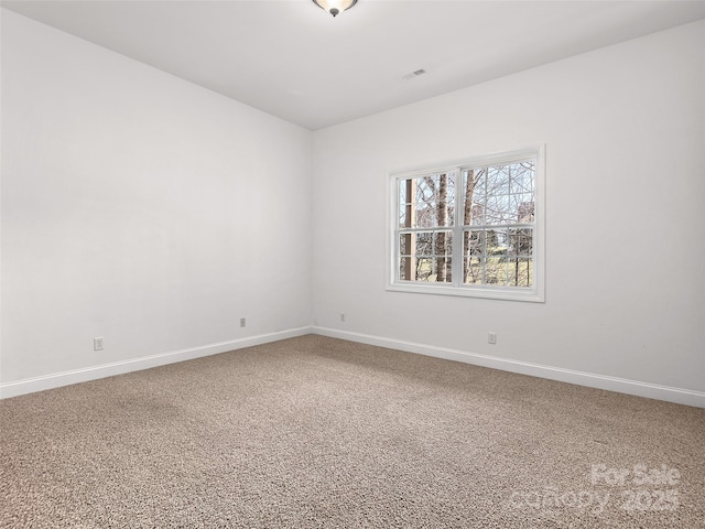 spare room featuring carpet floors, visible vents, and baseboards